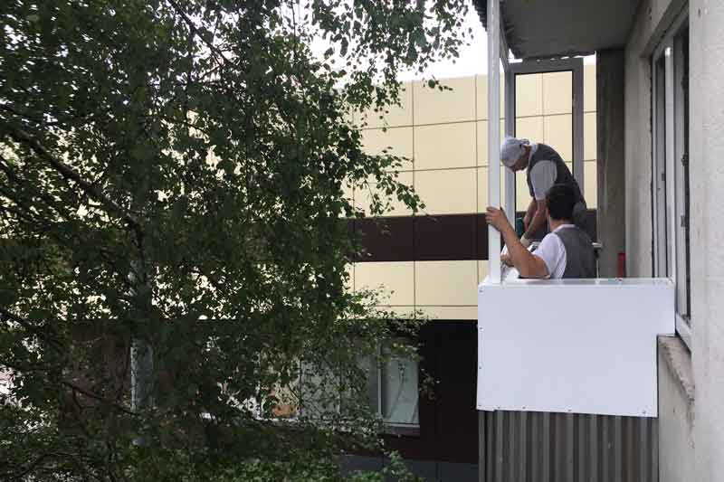 Мастера устанавливают рамы из алюминиевого профиля на балконе